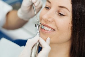 Person at a dentist's office, having their teeth examined for a deep teeth cleaning.